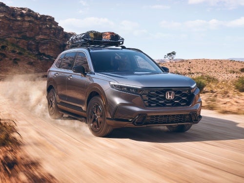2025 Honda CR-V driving down a dirt path with bags on roof rails